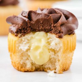 close up shot of a frosted cupcake showing it's inside Boston Cream pie filling