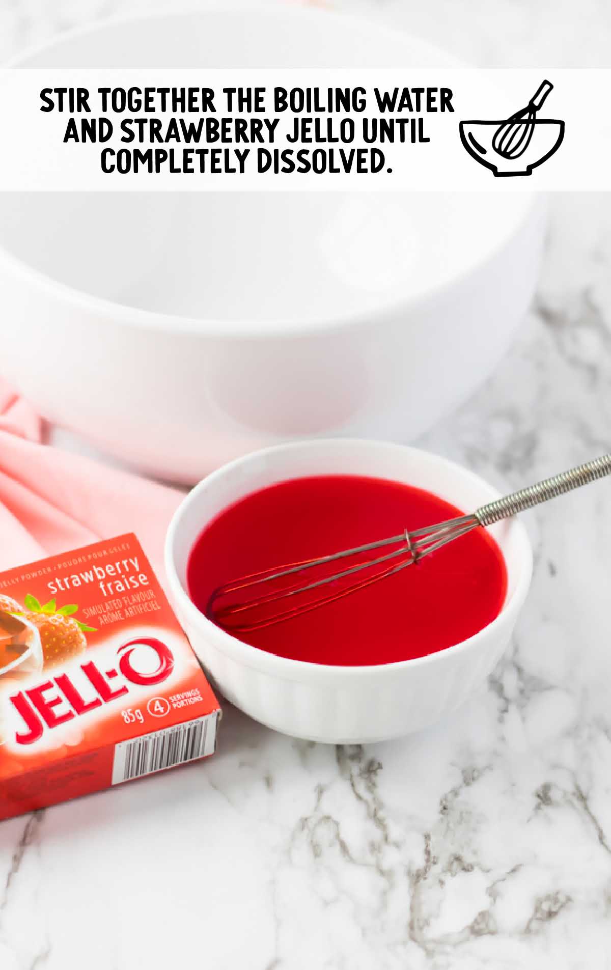 boiling water and strawberry jello whisked together in a bowl