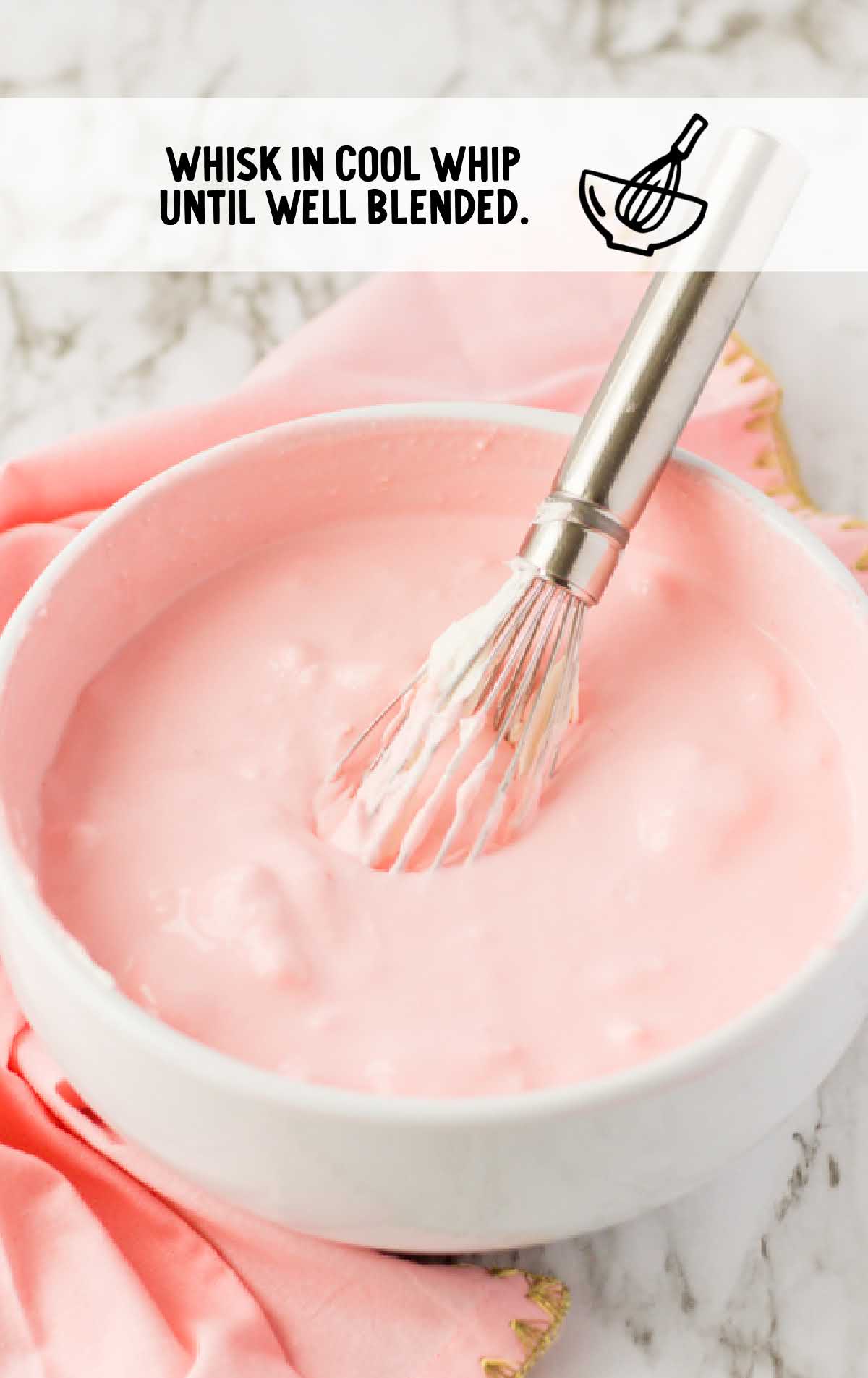 cool whip whisked into the strawberry jello mixture in a bowl