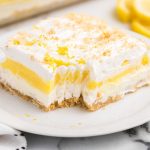 close up shot of a slice of Lemon Lasagna on a plate with a piece taken out of it with a fork
