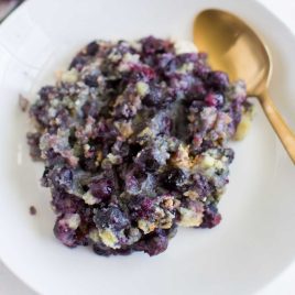close up overhead shot of a plate of blueberry cobbler with a spoon