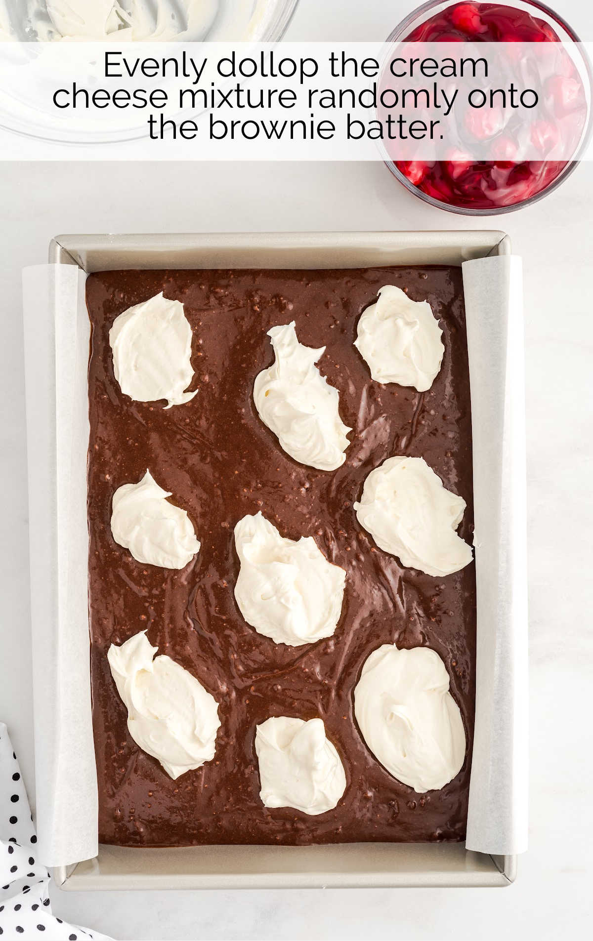drops of cream cheese mixture placed on top of the brownie batter in a baking pan
