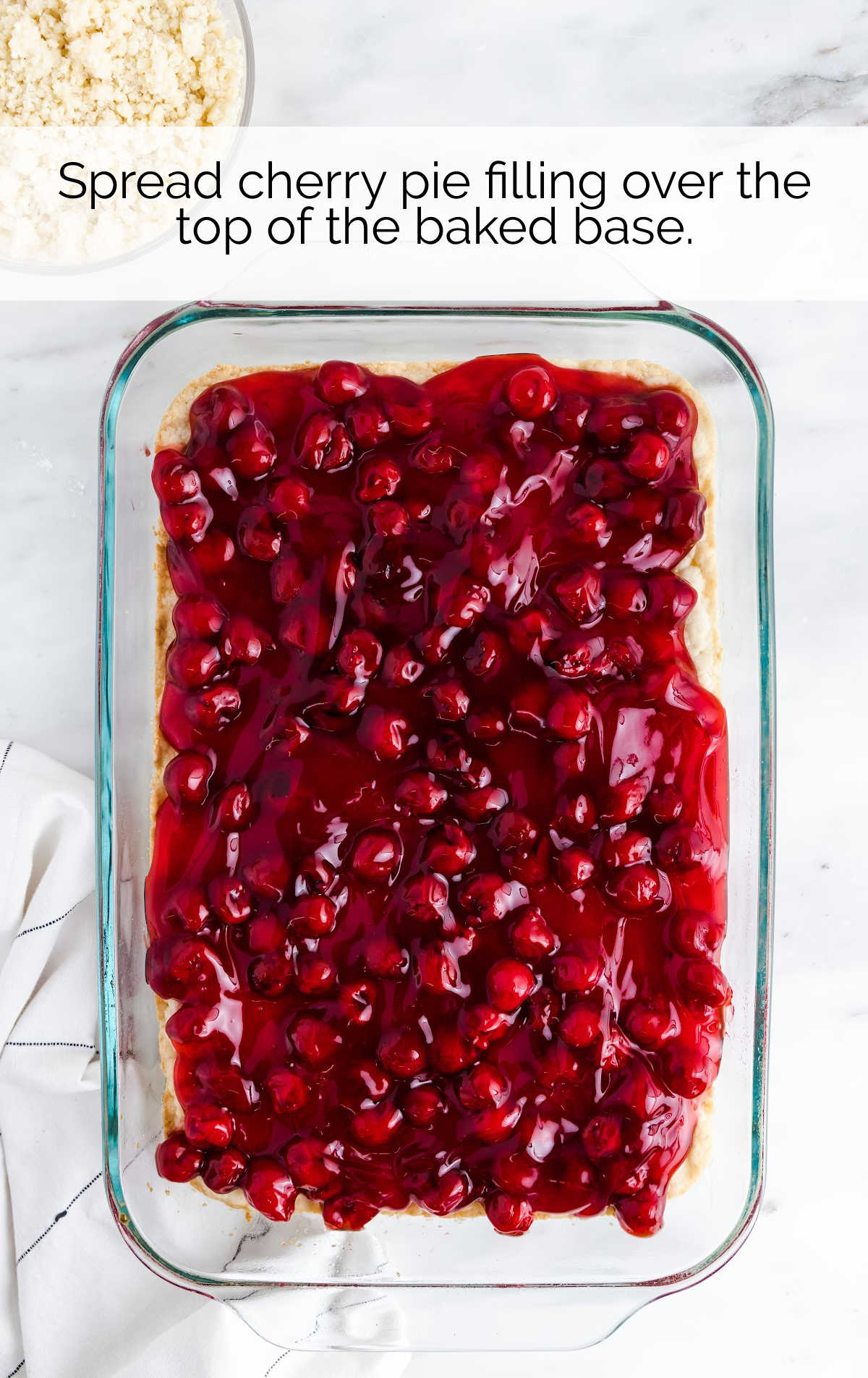 cherry pie filling spread on top of the dough in a baking dish