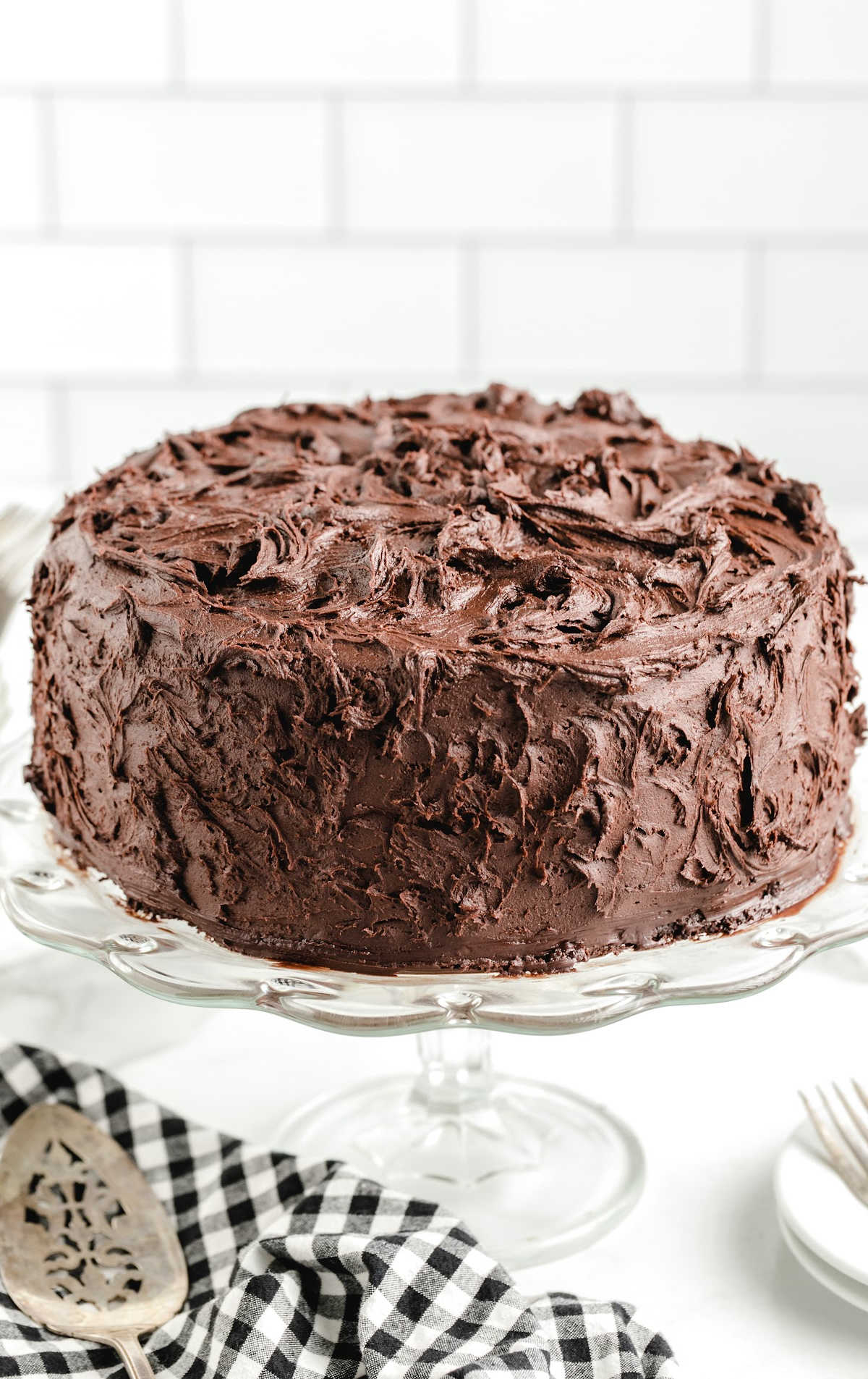 close up shot of a frosted chocolate cake on a cake stand