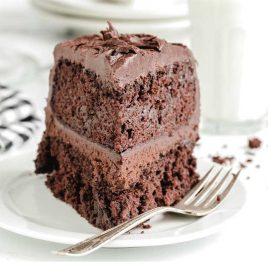 close up shot of a slice of frosted chocolate cake on a plate with a fork