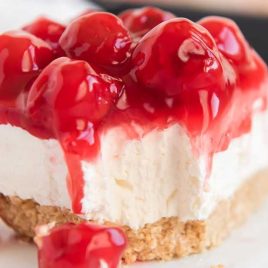 a slice of cheesecake topped with cherry pie filling on a plate