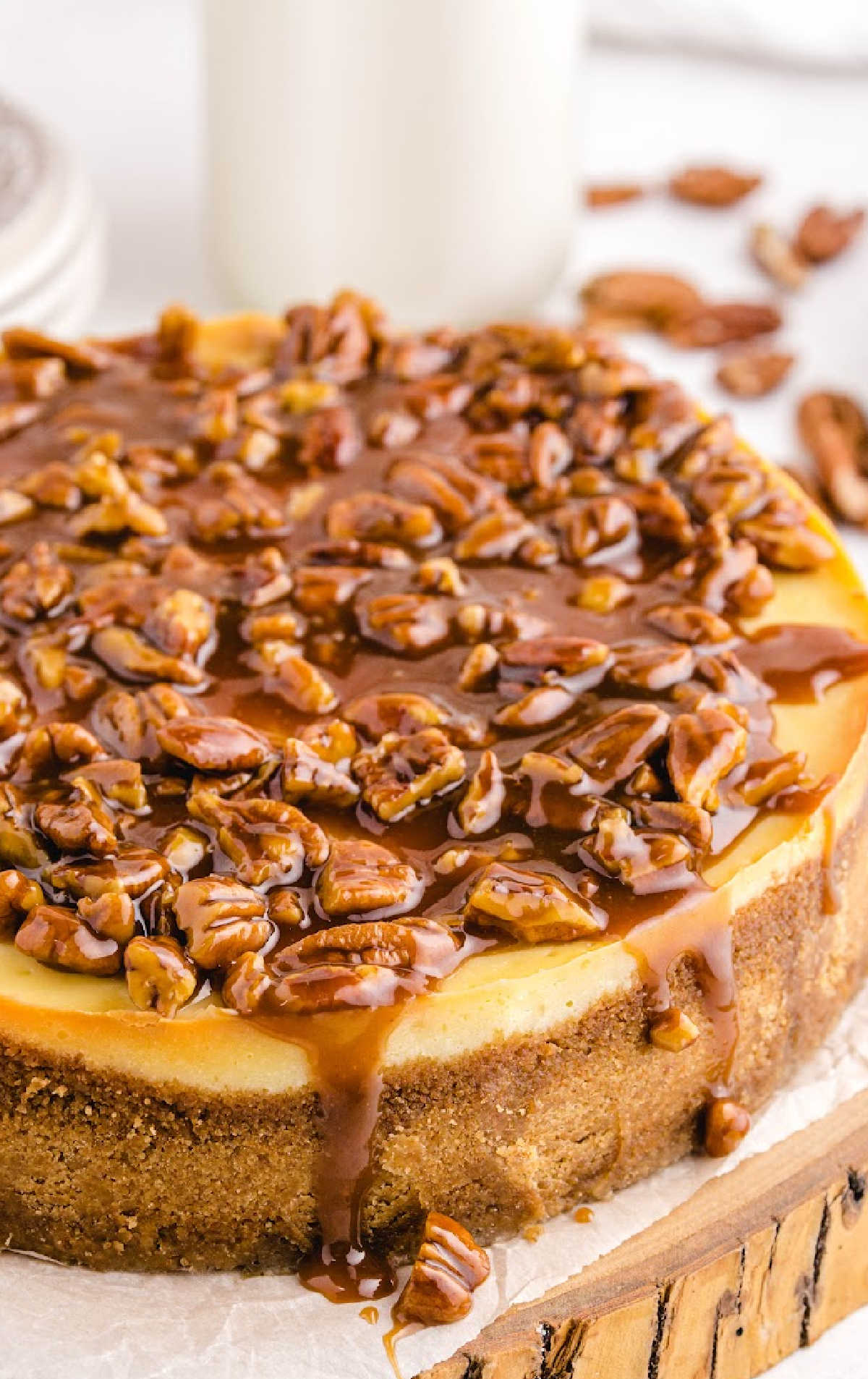 close up shot of a cheesecake topped with pecans and caramel glaze
