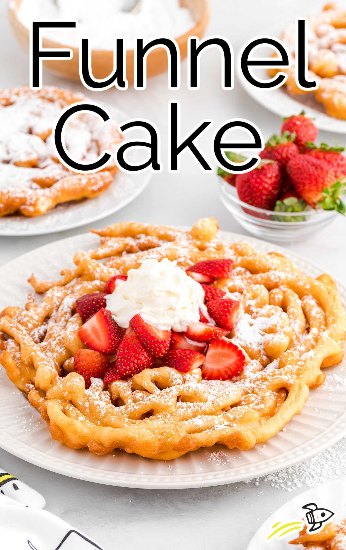 Funnel Cake topped with strawberries, powdered sugar, and whip cream on a plate