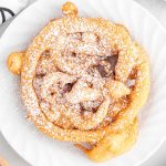 close up over head shot of Funnel Cake topped with powdered sugar on a plate
