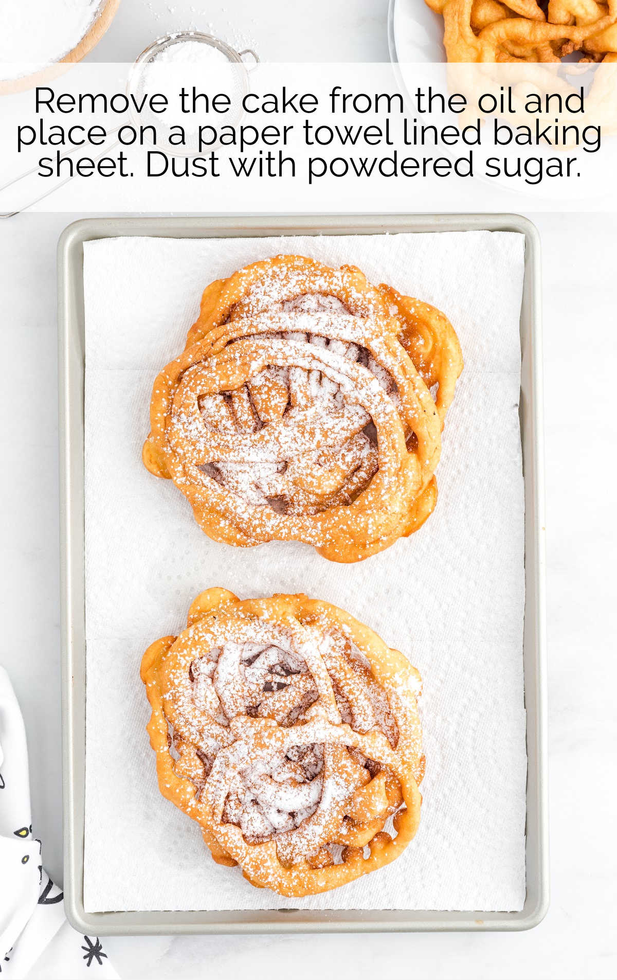 Funnel Cake topped with powdered sugar on a parchment line pan