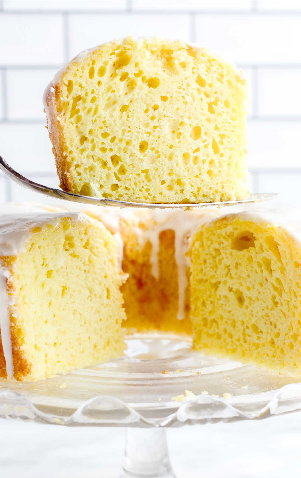 a piece of Lemon Chiffon Cake on a spoon and Lemon Chiffon Cake on a cake stand
