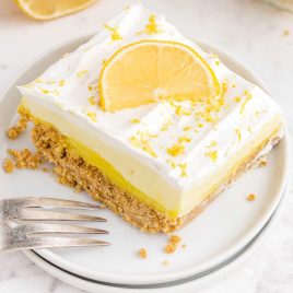 close up shot of a slice of Lemon Pie topped with a slice of lemon on a plate