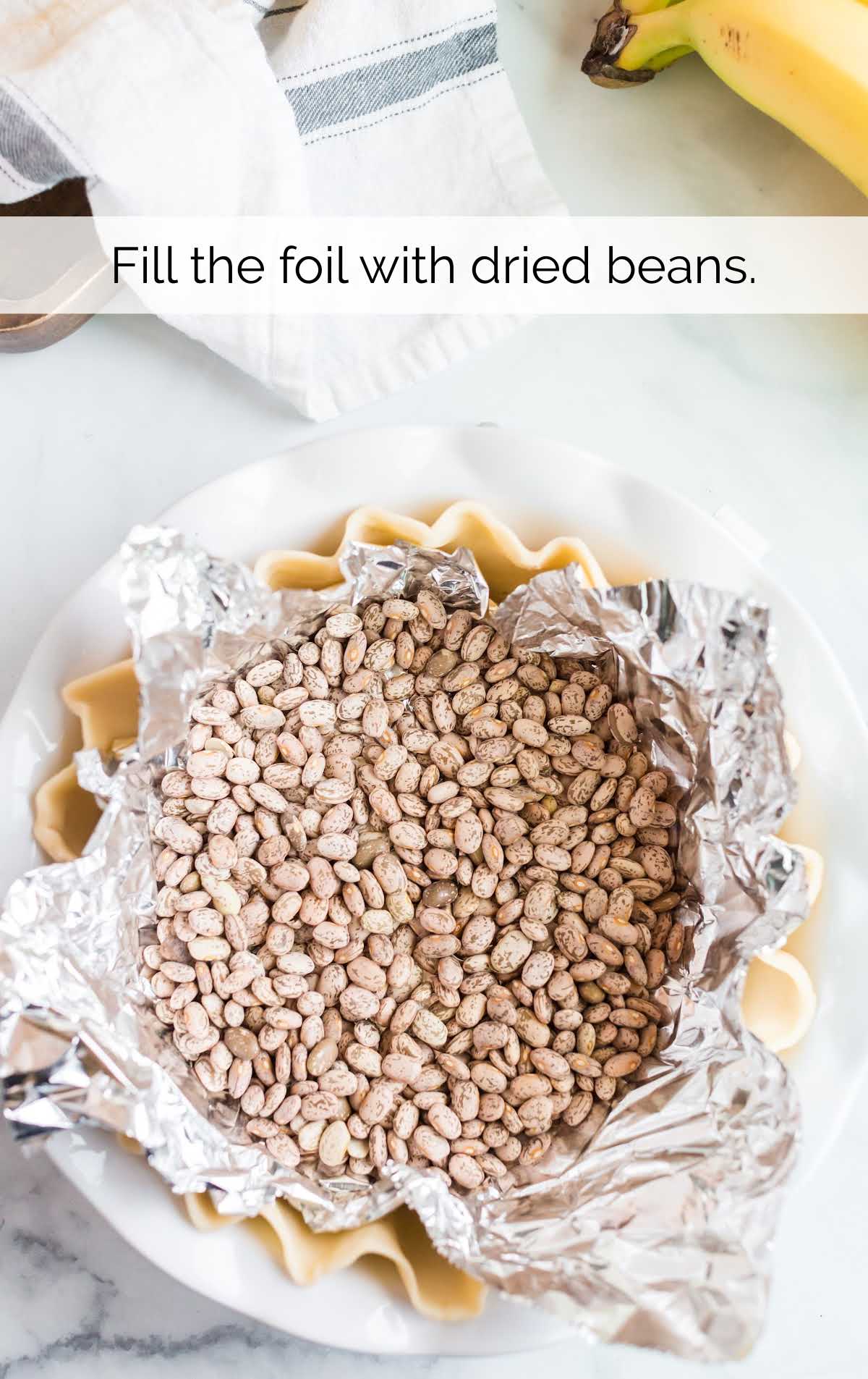 dried beans on foil in a pie crust and baking dish