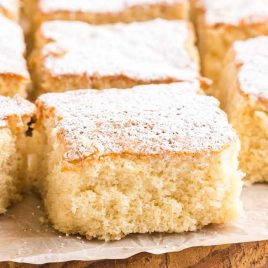 close up shot of Slices of Milk Cake sprinkled with powder sugar on a cutting board