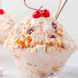 a bunch of Ambrosia Salads topped with a cherry in a bowl