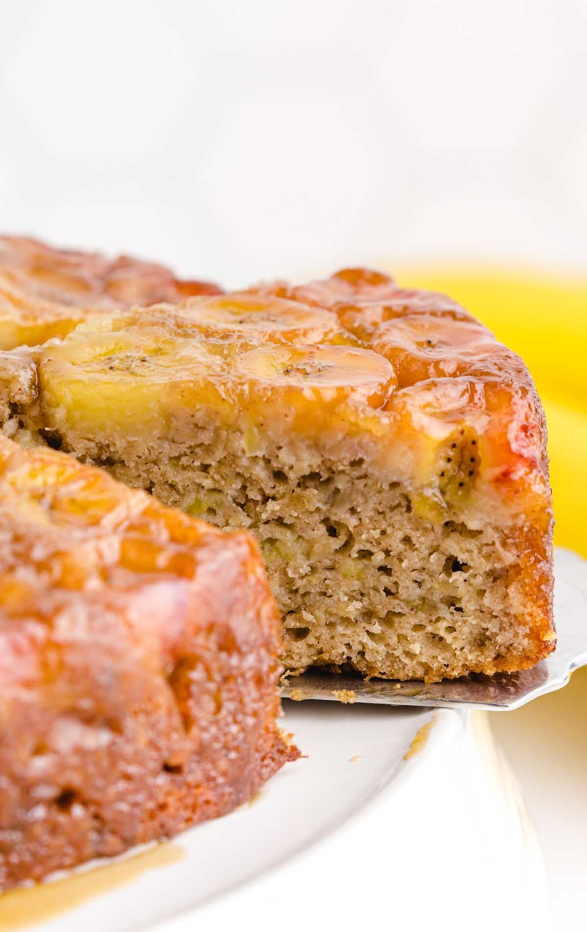 close up shot of Banana Upside Down Cake with a cake cutter getting a slice