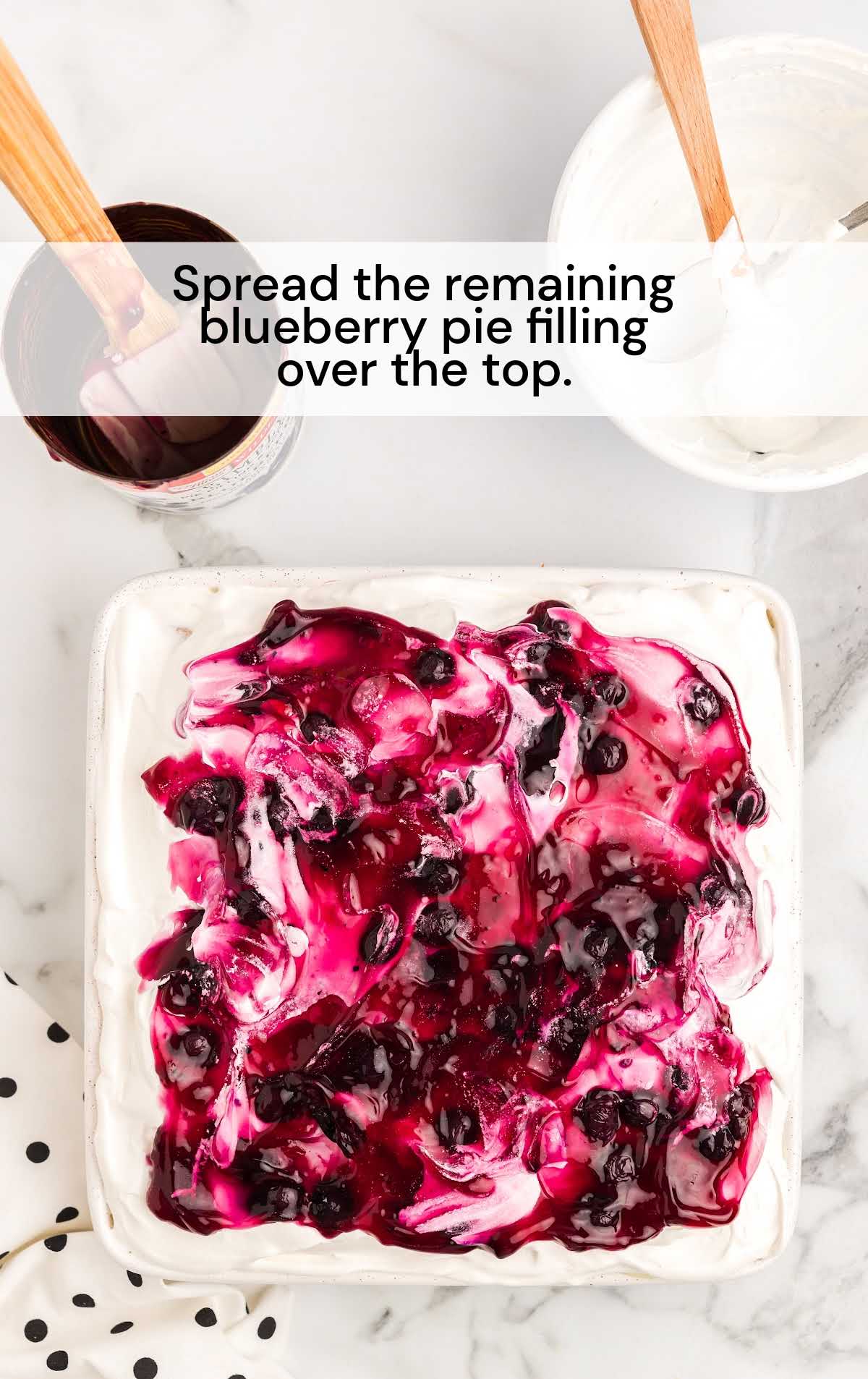 blueberry pie filling spread over the top of the cake in a baking dish