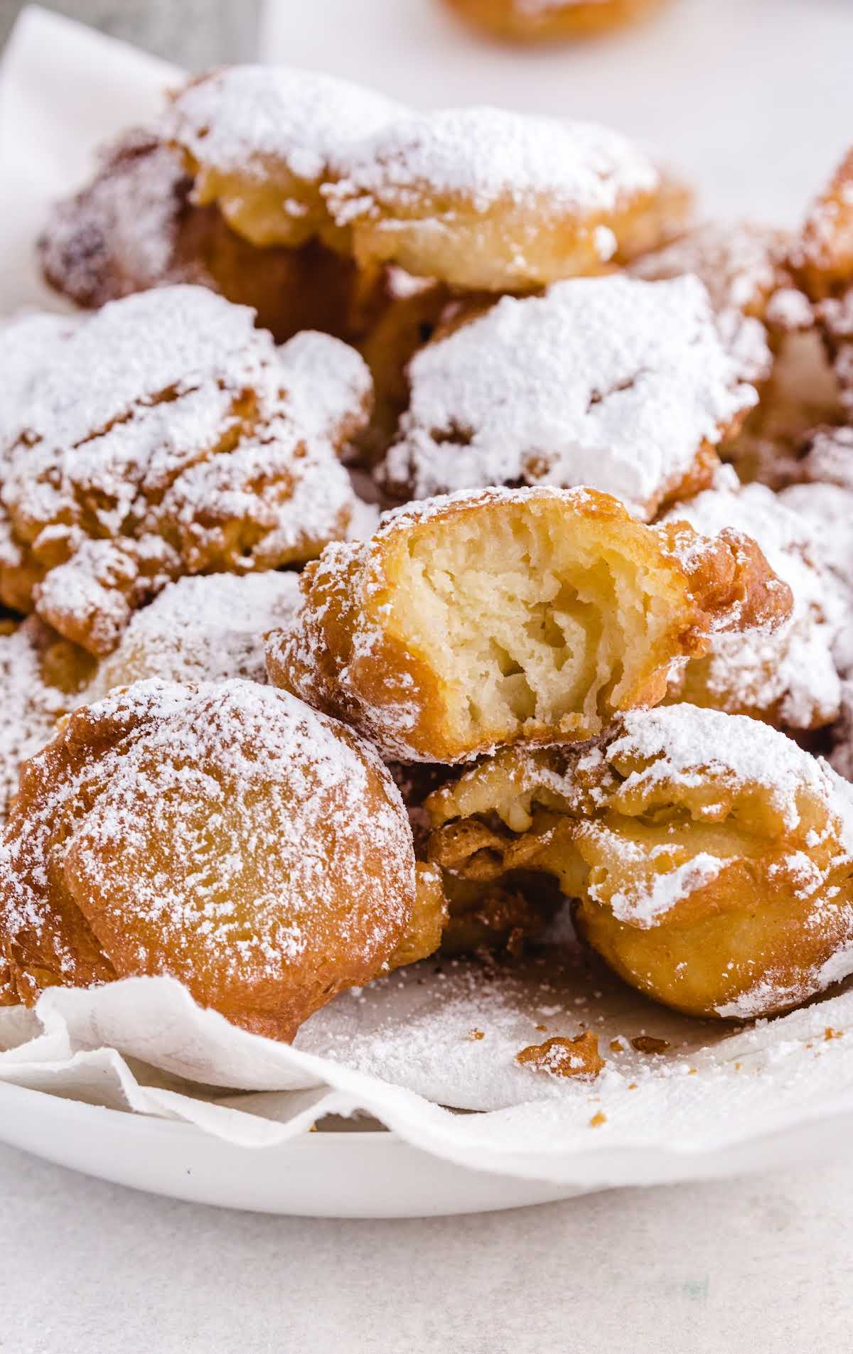 close up shot of Funnel Cake Bites on a plate with one having a bite taken out of it
