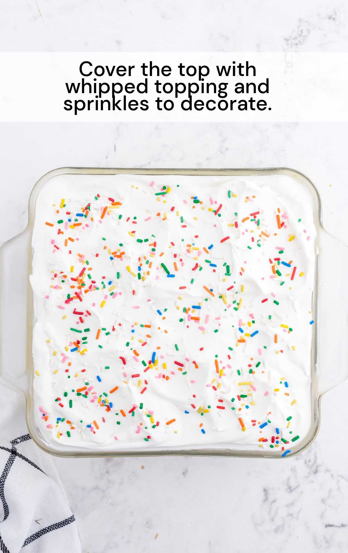 whipped topping and sprinkles places over the top if the cake in a baking dish