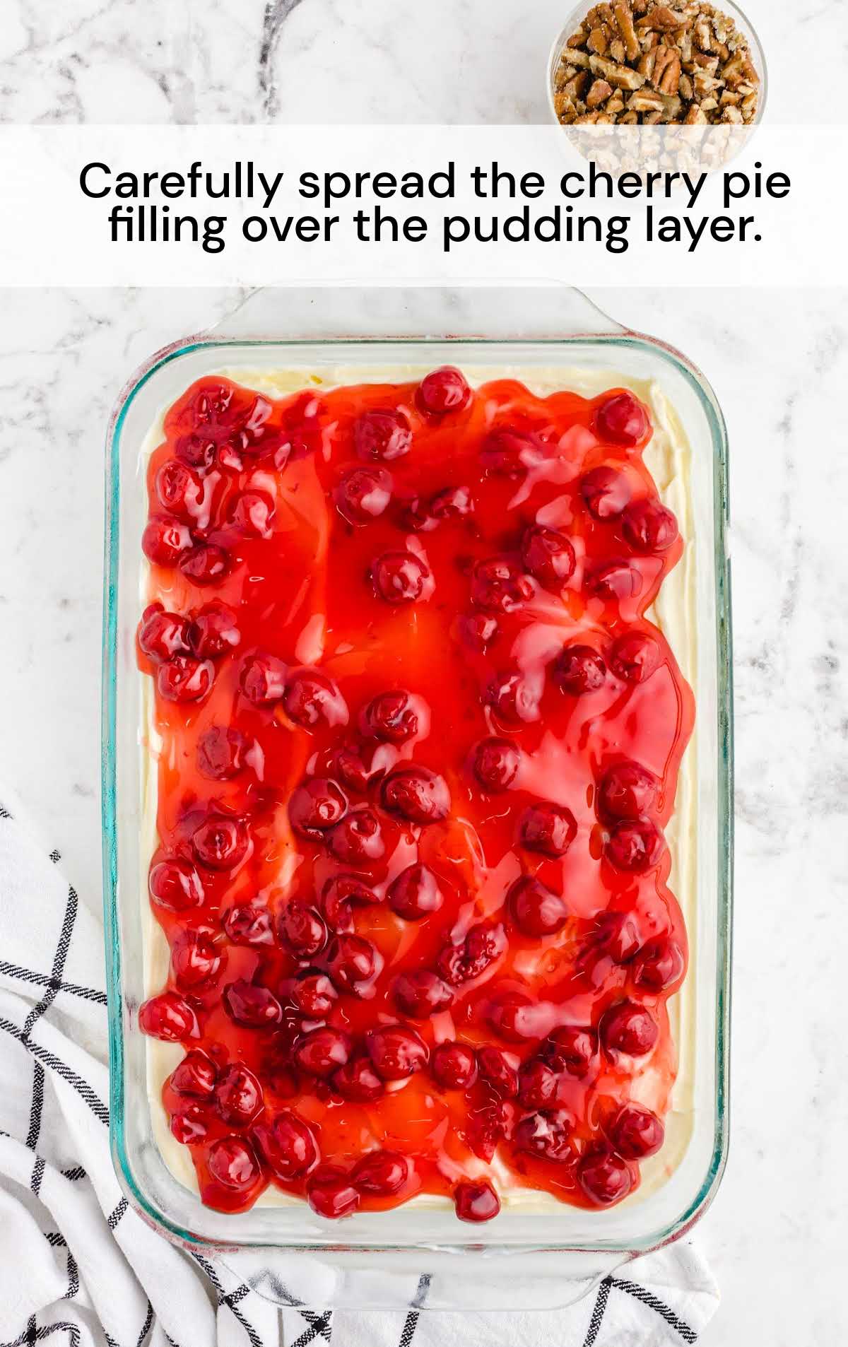 cherry pie filling spread over the pudding layer in a baking dish