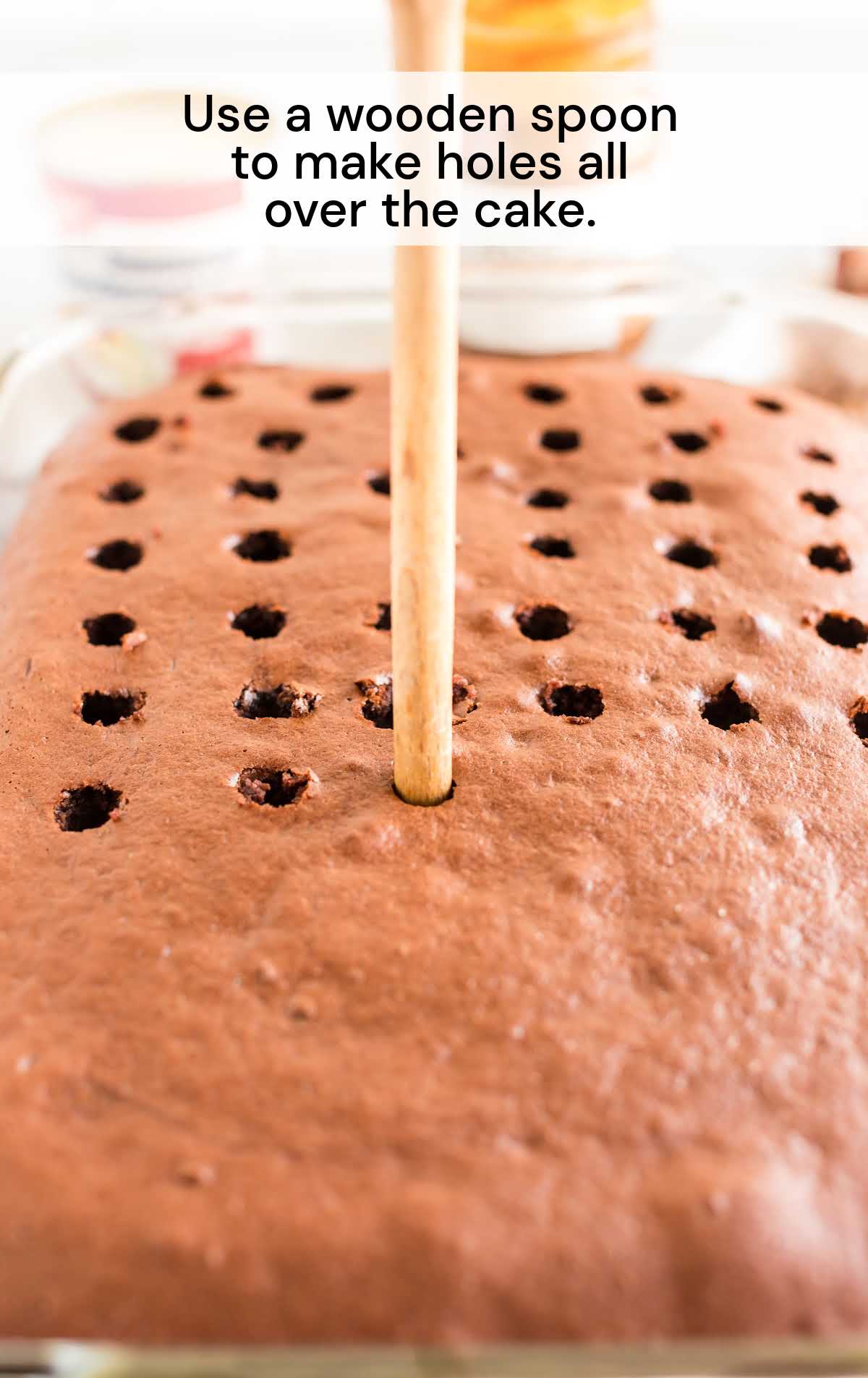 making holes on the cake using a wooden spoon